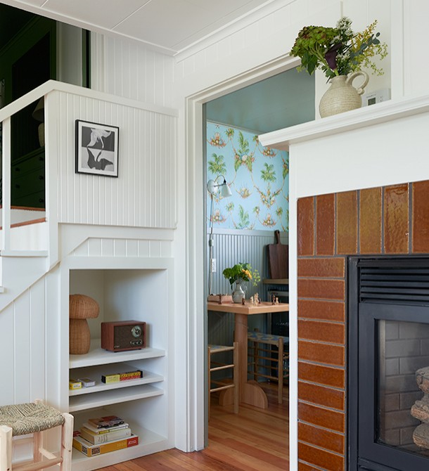 A close up of shelves under the staircase next to a table with chess pieces on top.
