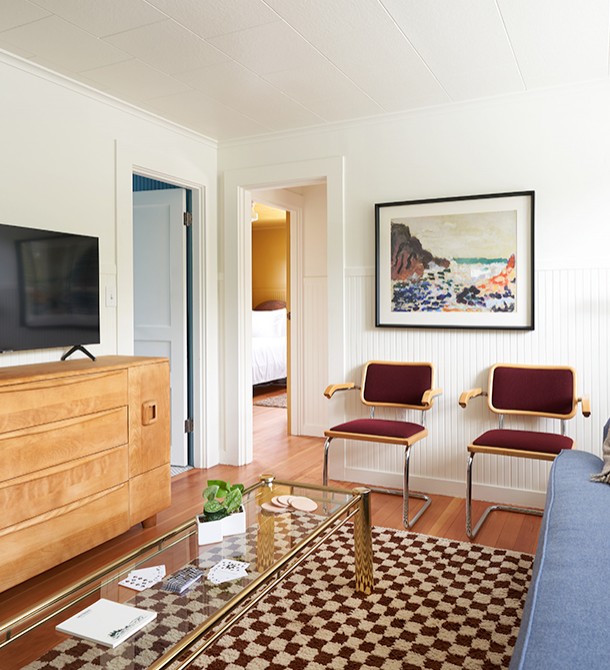 Two red chairs and artwork hanging on the wall above them.