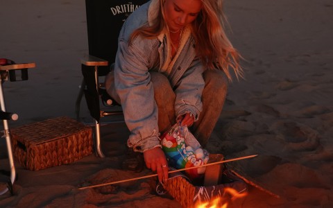 a woman sitting on a chair and lighting a fire