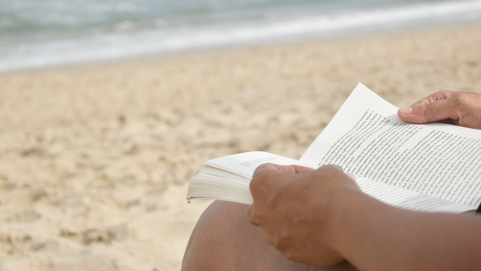 a person reading a book on a beach