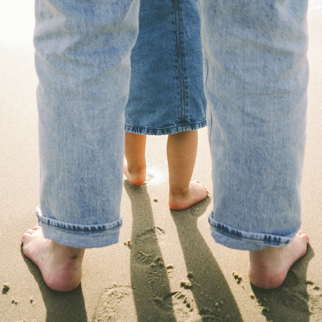 a person's legs and feet on the sand