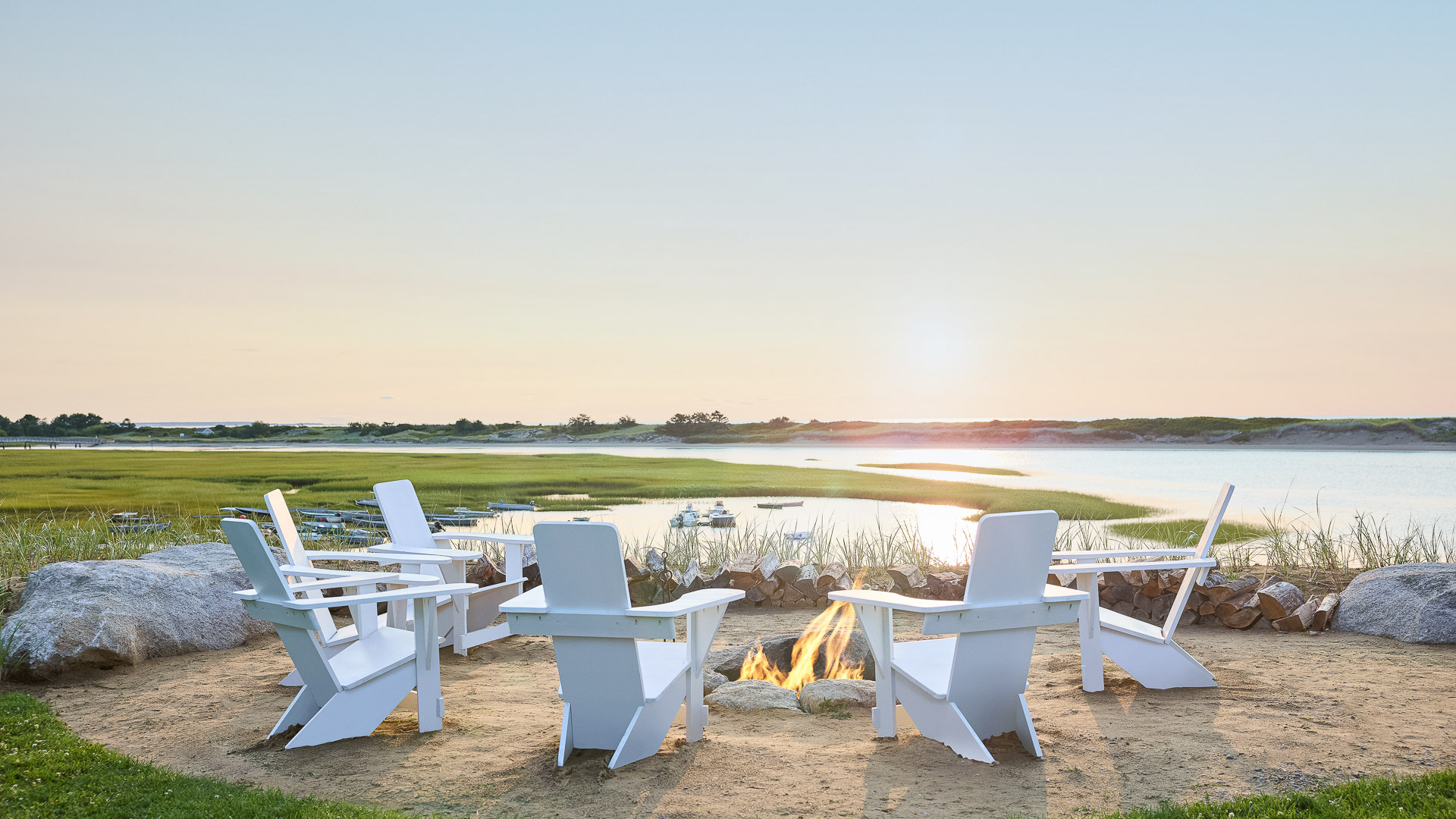 chairs and chairs around a fire pit by a body of water