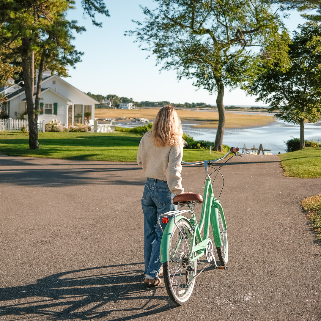 a woman walking with a bicycle on a road