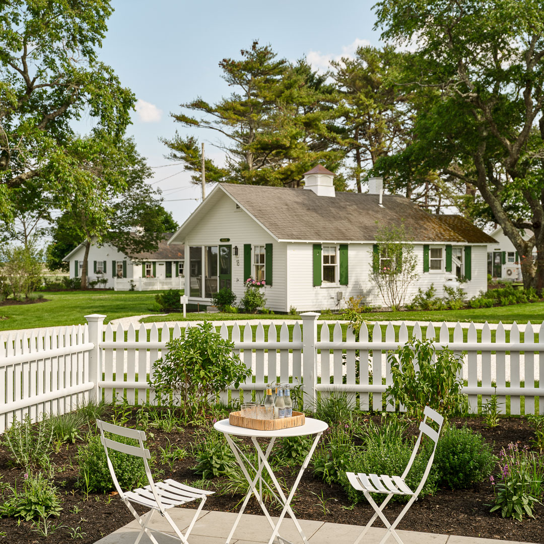 a white picket fence with a table and chairs in front of a house