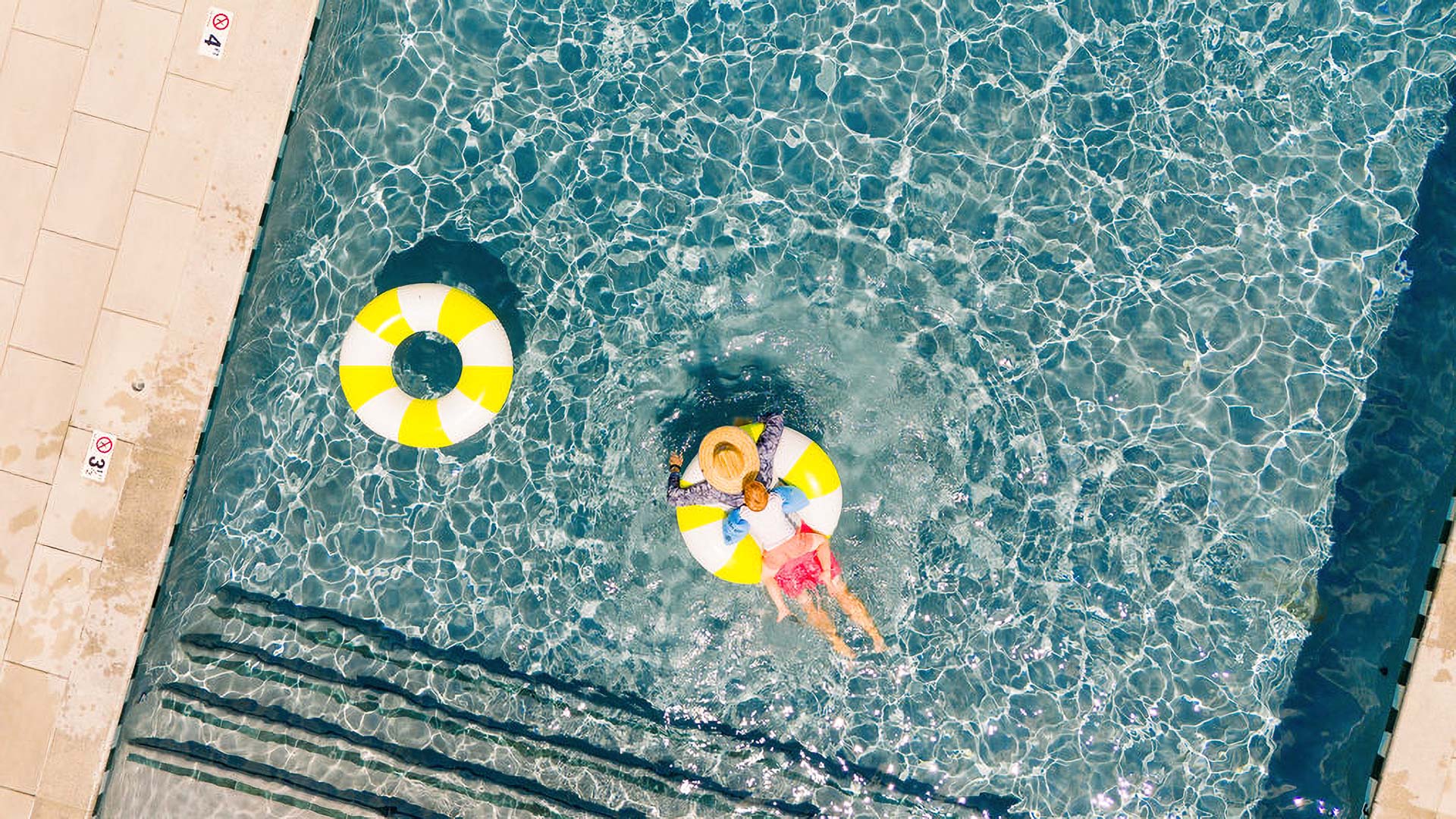 a woman floating on a yellow and white float tube in a pool