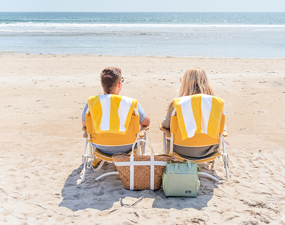 a man and woman sitting in chairs on a beach