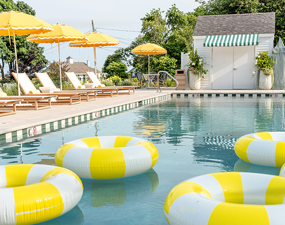 a pool with yellow and white inner tubes and umbrellas