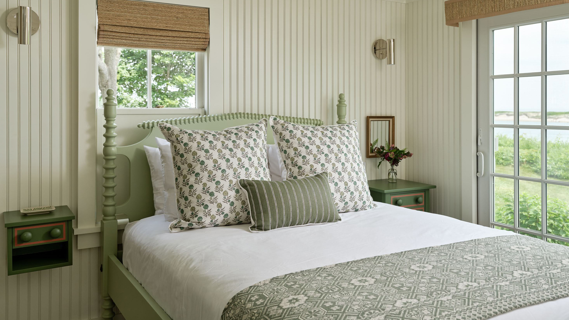 a bed with pillows and a vase of flowers