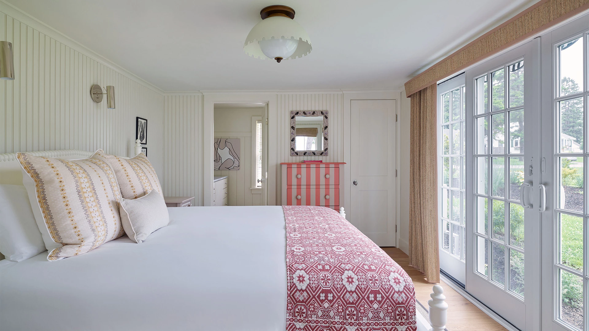 A white bedroom with a bed, dresser, and door leading outside.