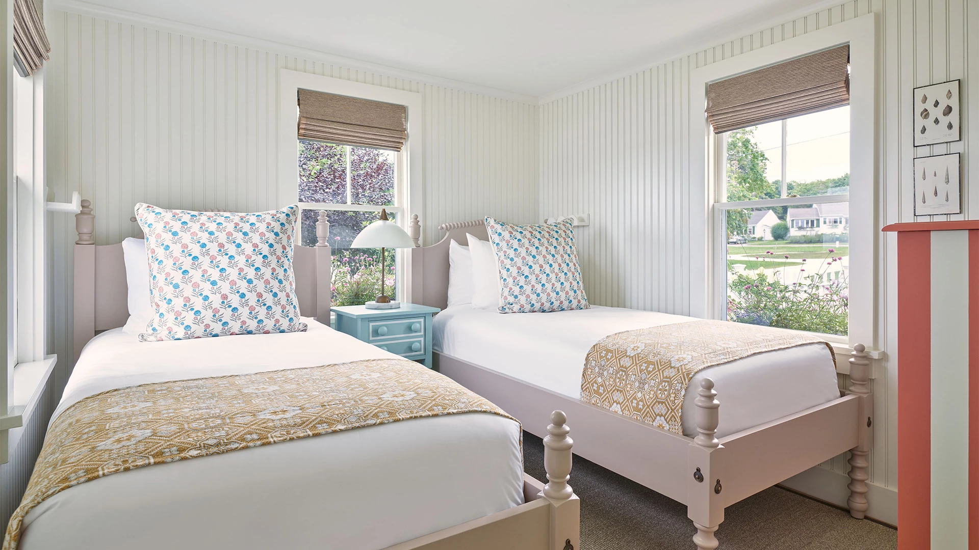 A bright and airy room with two twin beds, white bedding, and floral pillows.