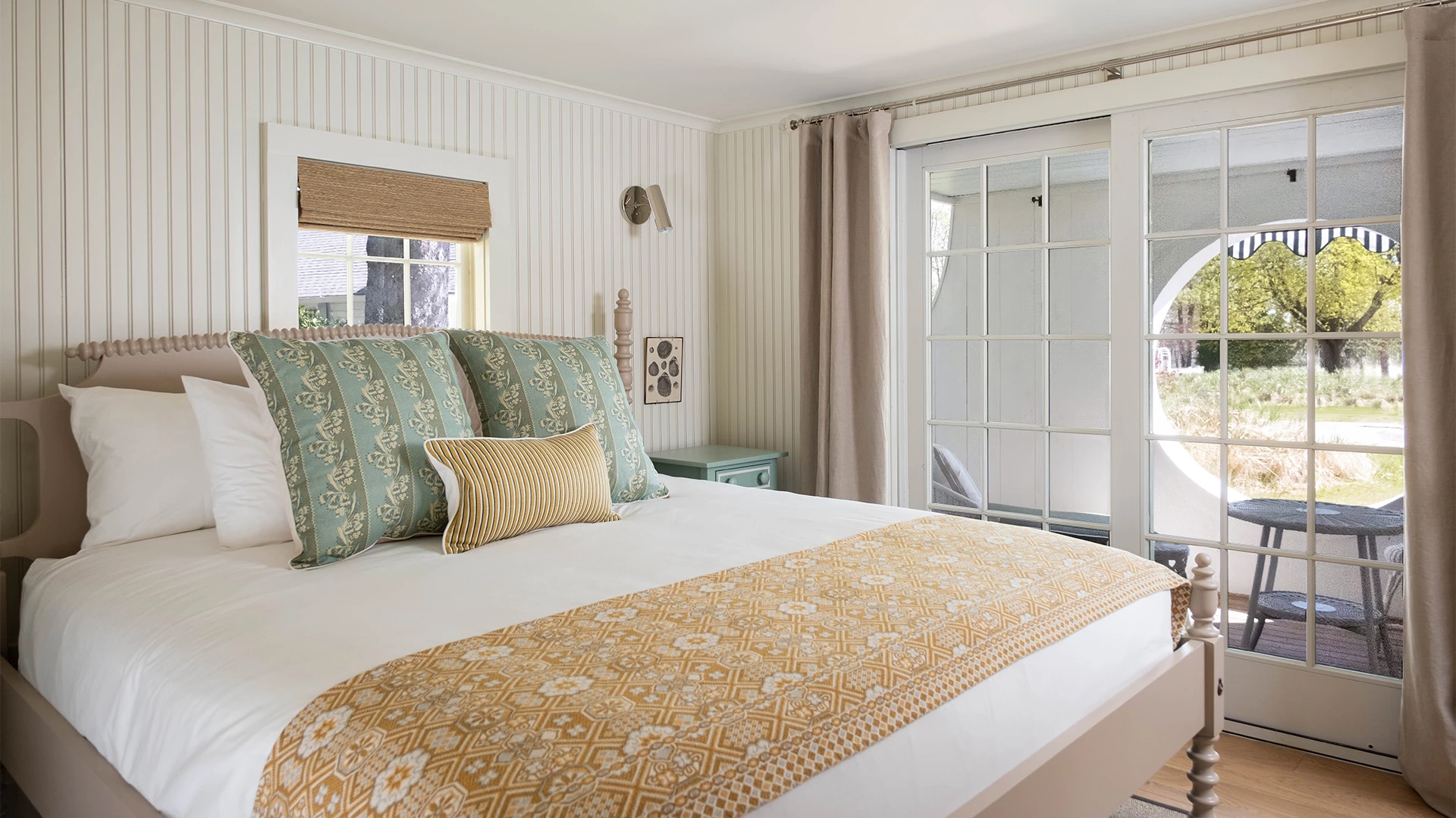 A wide view of a hotel room with a bed, window, and door.