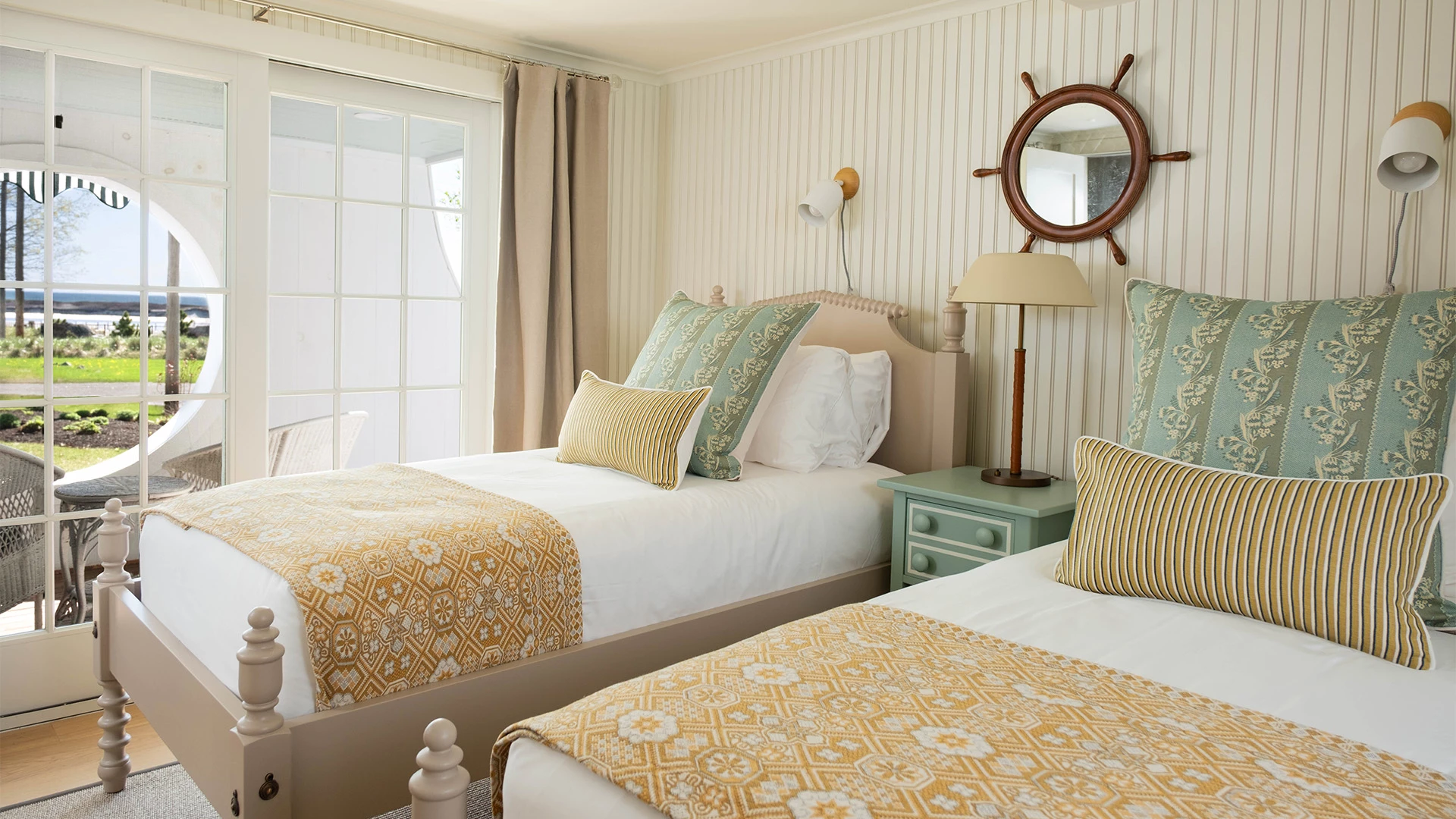 A bright and inviting room with two beds, a nightstand, and a view of the outdoors.