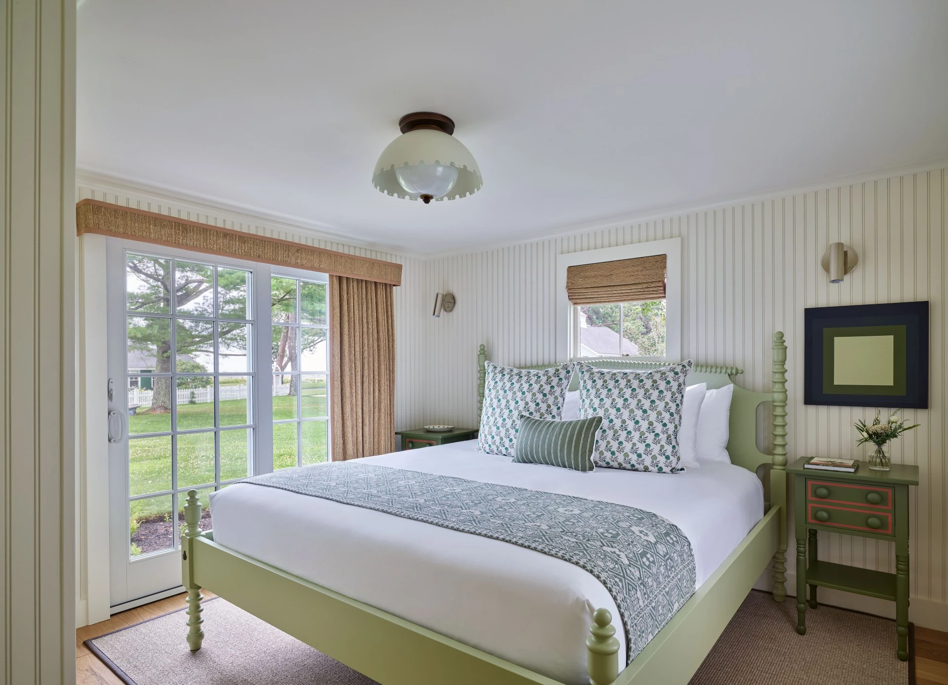 A wide view of a bedroom with a large bed, two nightstands, and a door leading outside.