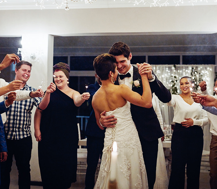 a bride and groom dancing while others watch and hold lit sparklers