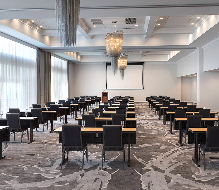 a podium and projection screen in a meeting space with many rows of tables and chairs