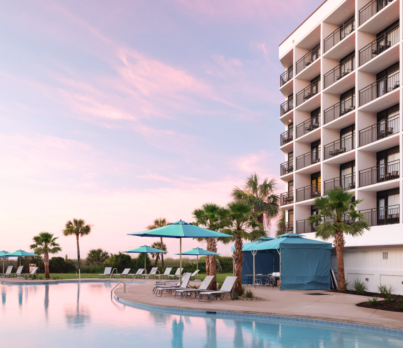 a pool with umbrellas and chairs in front of a building