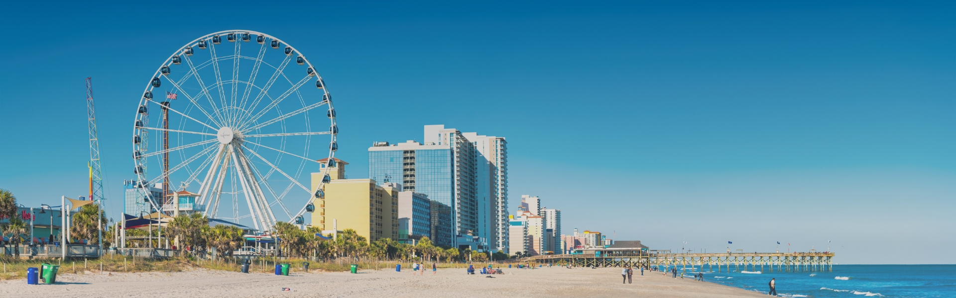 a beach with buildings and a ferris wheel