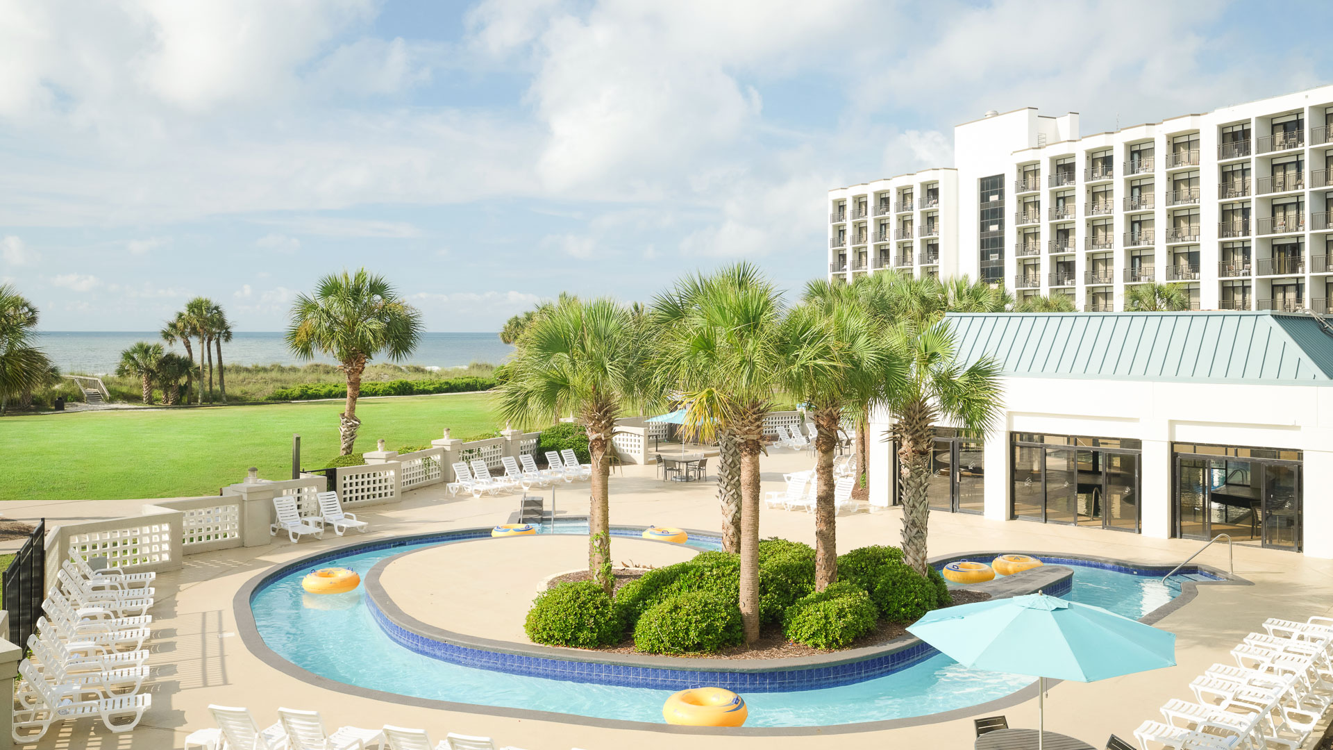 a pool with palm trees and a pool in front of a hotel