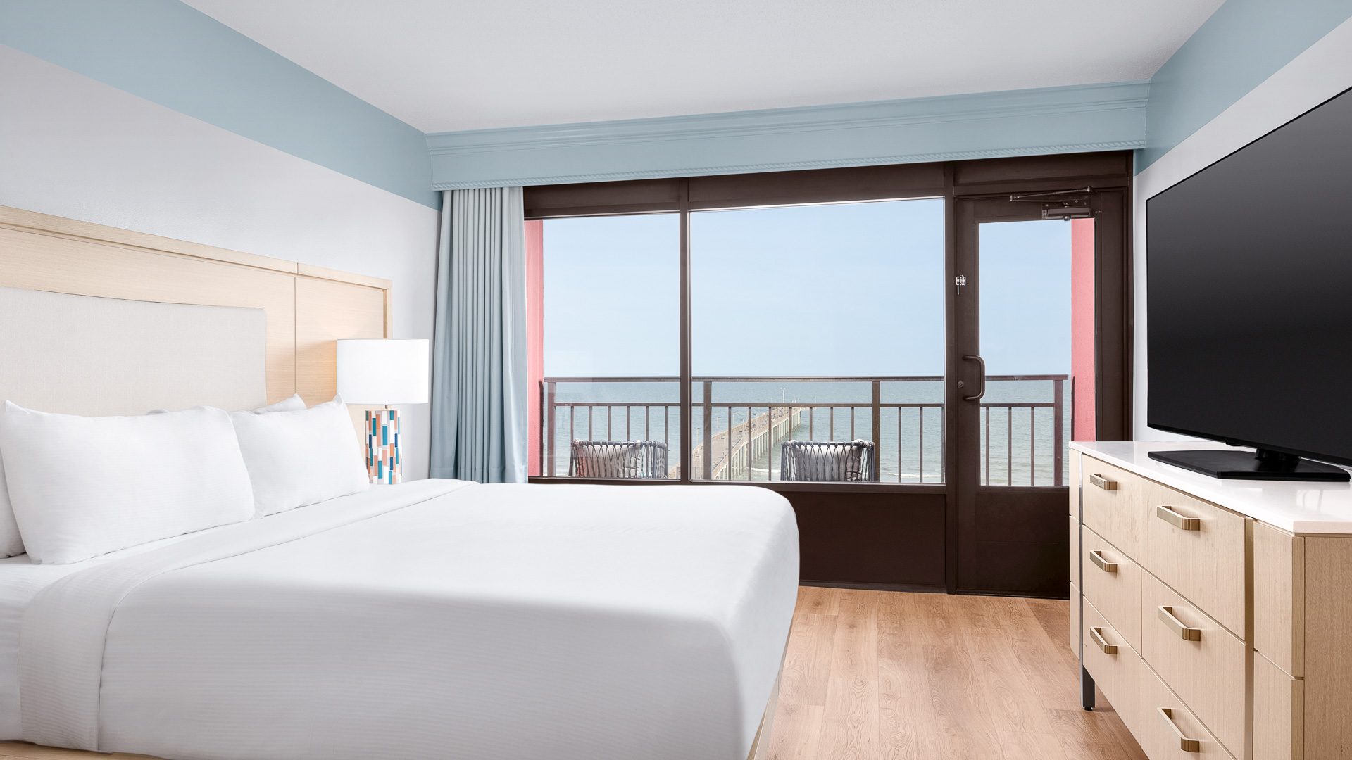 a hotel room with a balcony and a view of the ocean