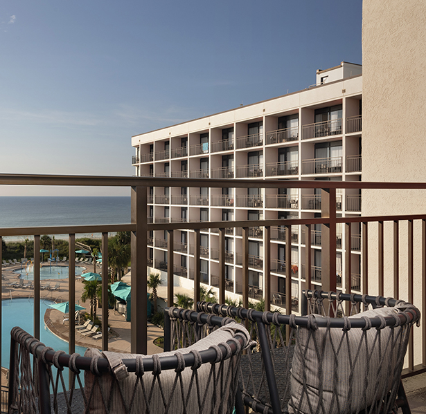 a balcony with chairs and a pool in the background