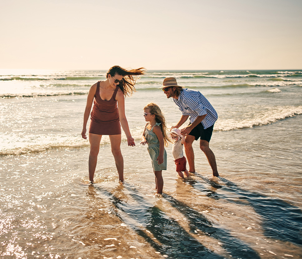 a group of people standing in the water on a beach