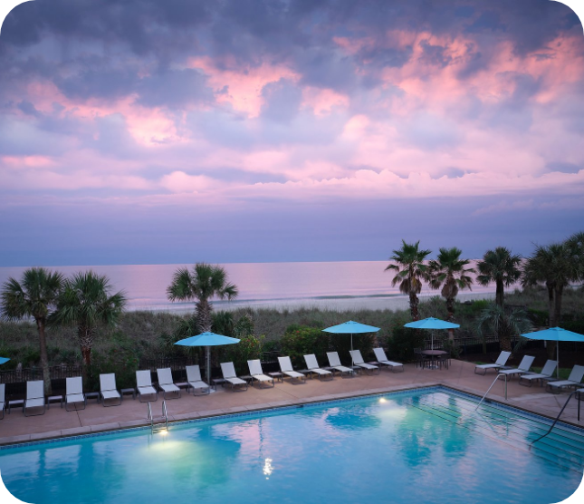 a pool with umbrellas and chairs by the water