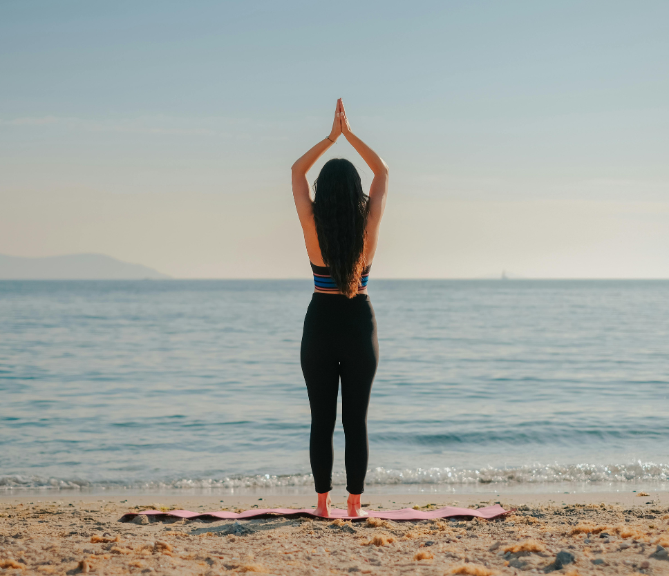 a woman standing on a beach with her hands over her head