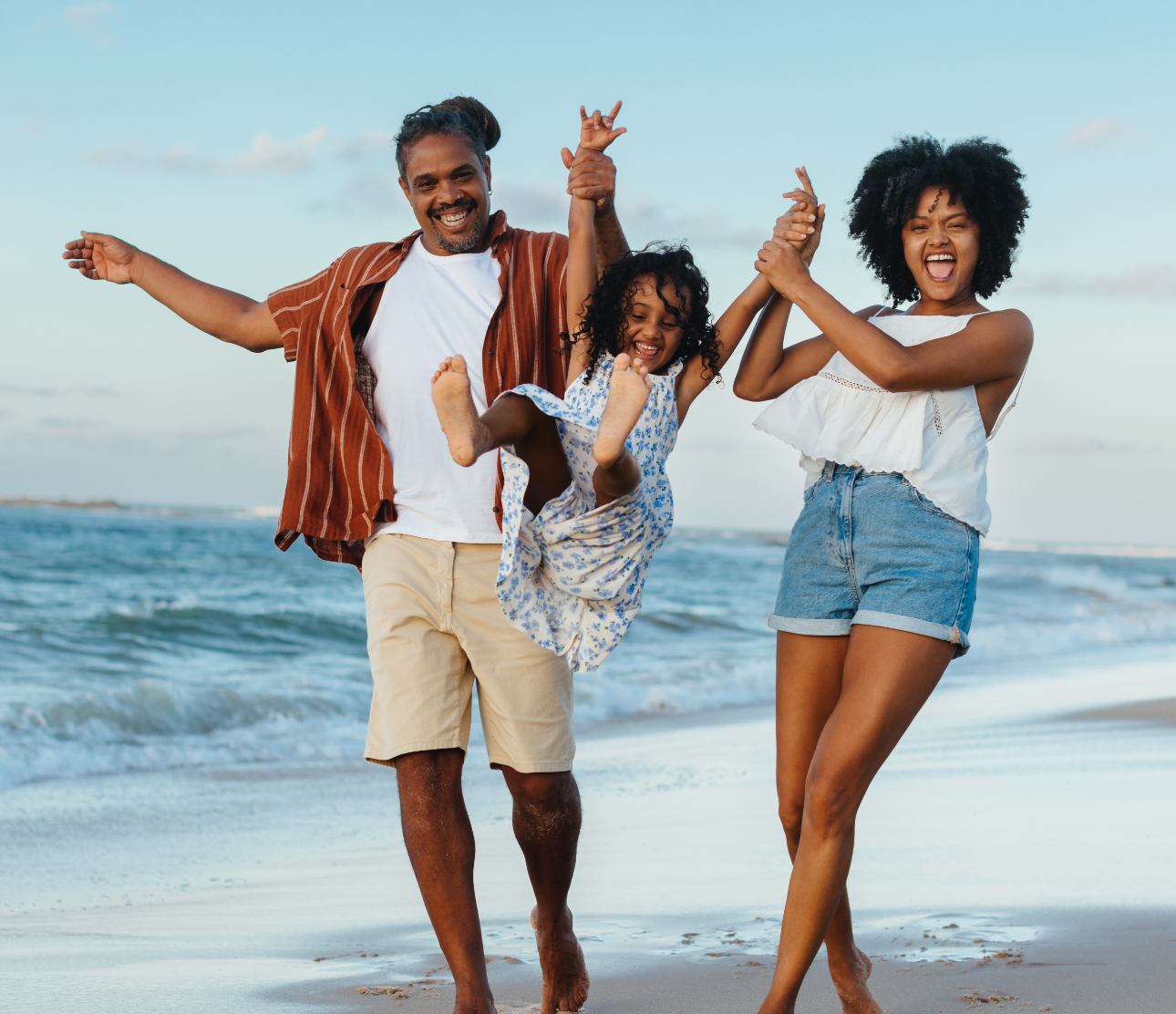 a man and woman holding hands and jumping on a beach