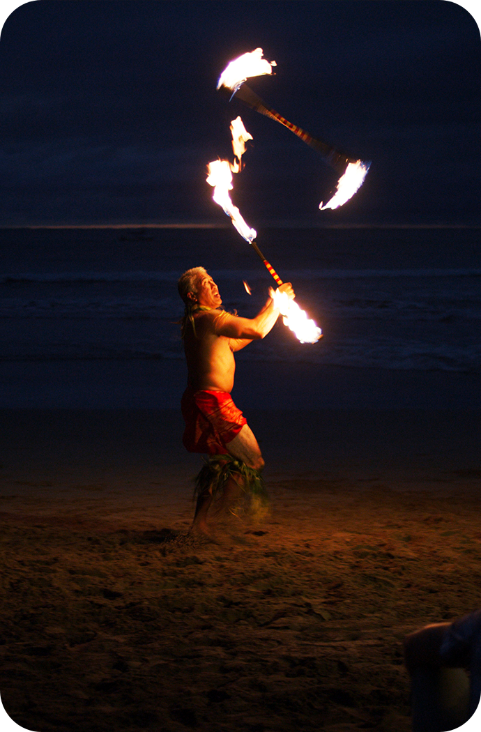 a man holding fire sticks at night