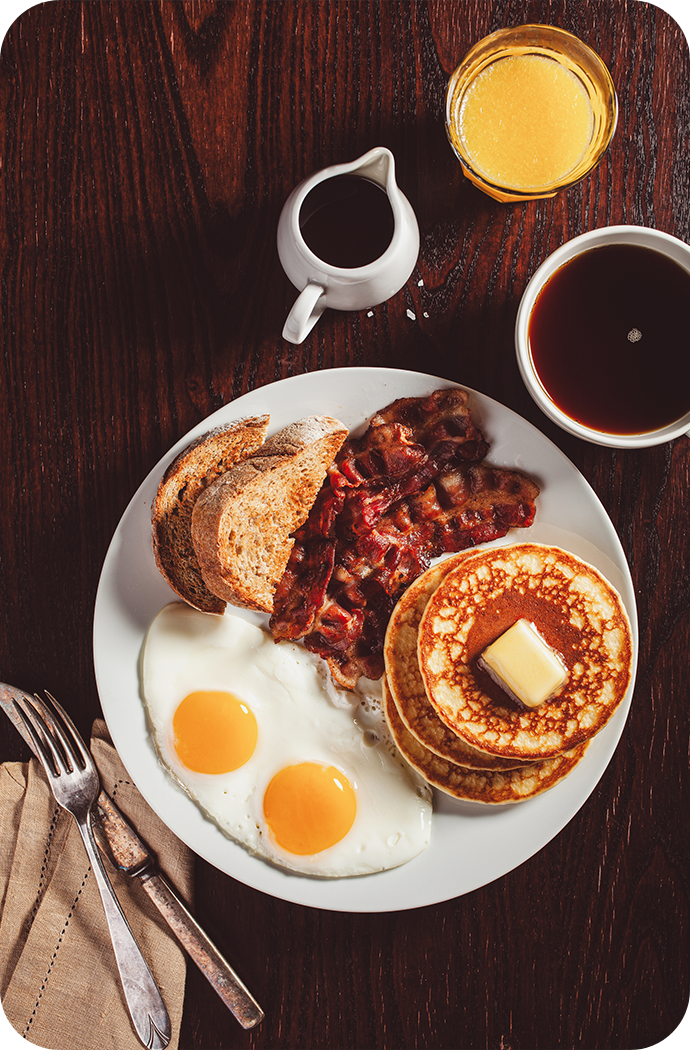 a plate of breakfast with eggs bacon pancakes and pancakes