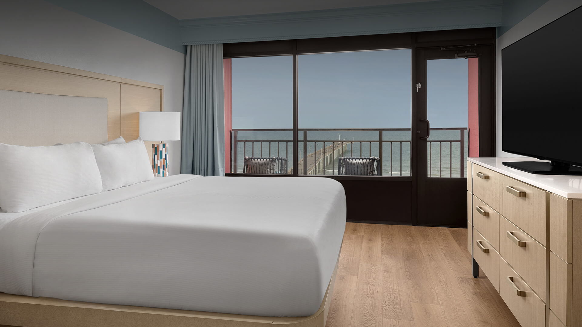 a room with a bed and a balcony overlooking the ocean