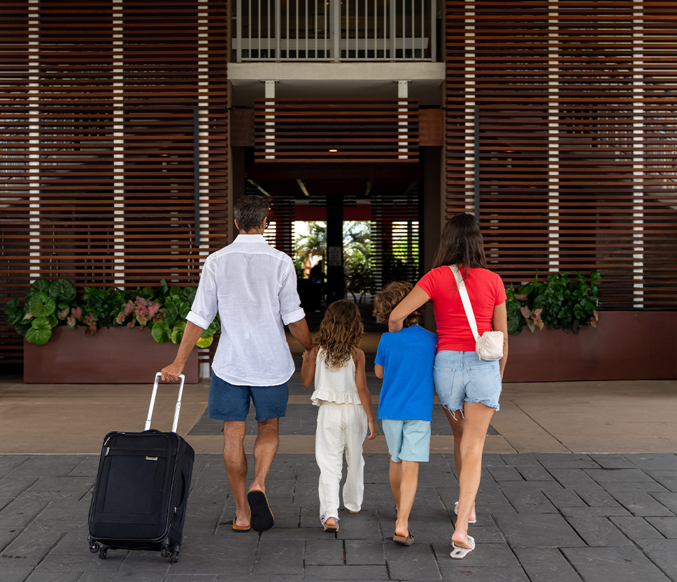 a family walking with luggage in front of a building