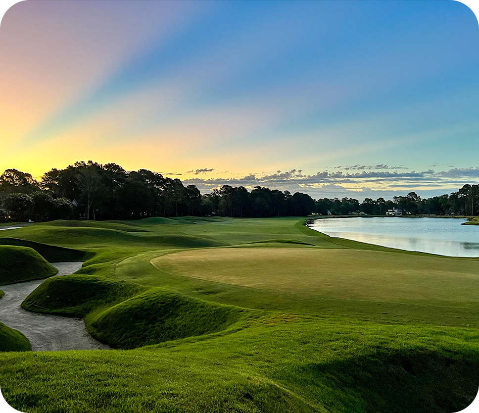 a golf course with a body of water and trees