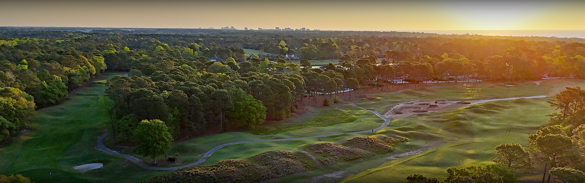 a golf course with trees and a city in the background