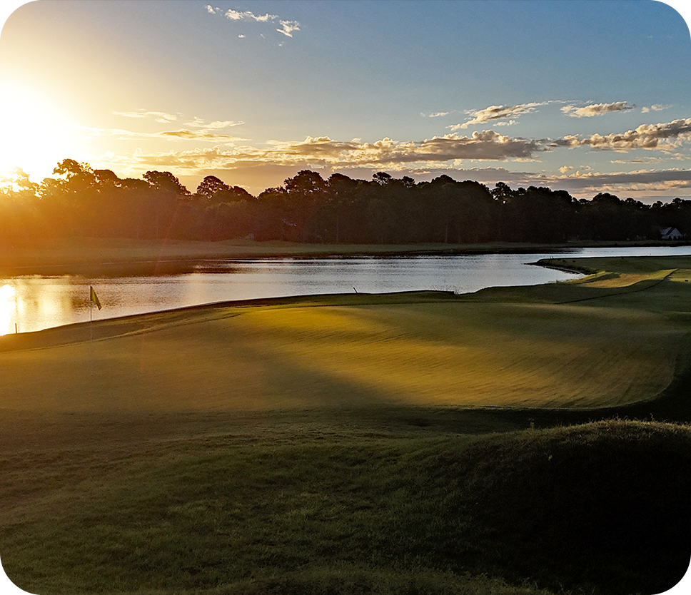 a golf course with a lake and trees in the background