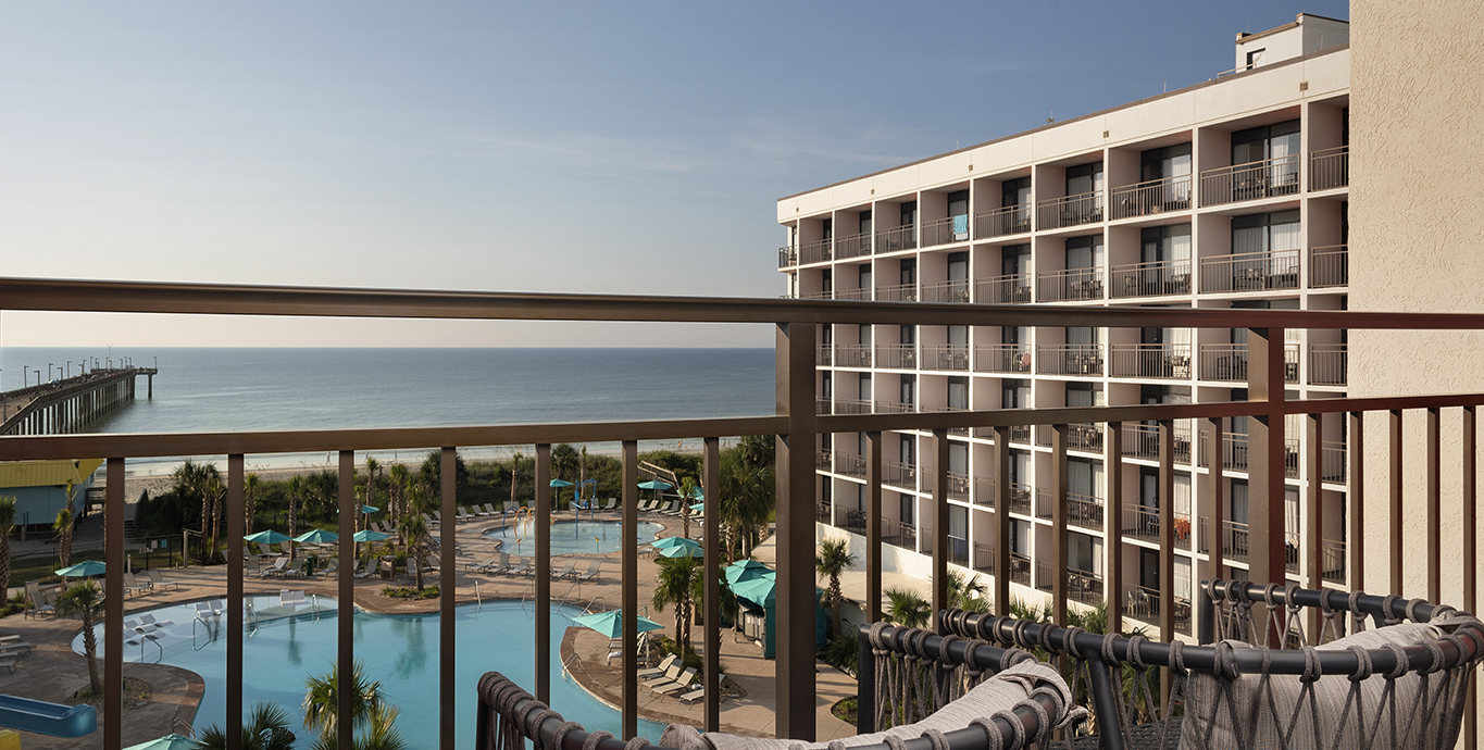 a balcony with a pool and a hotel