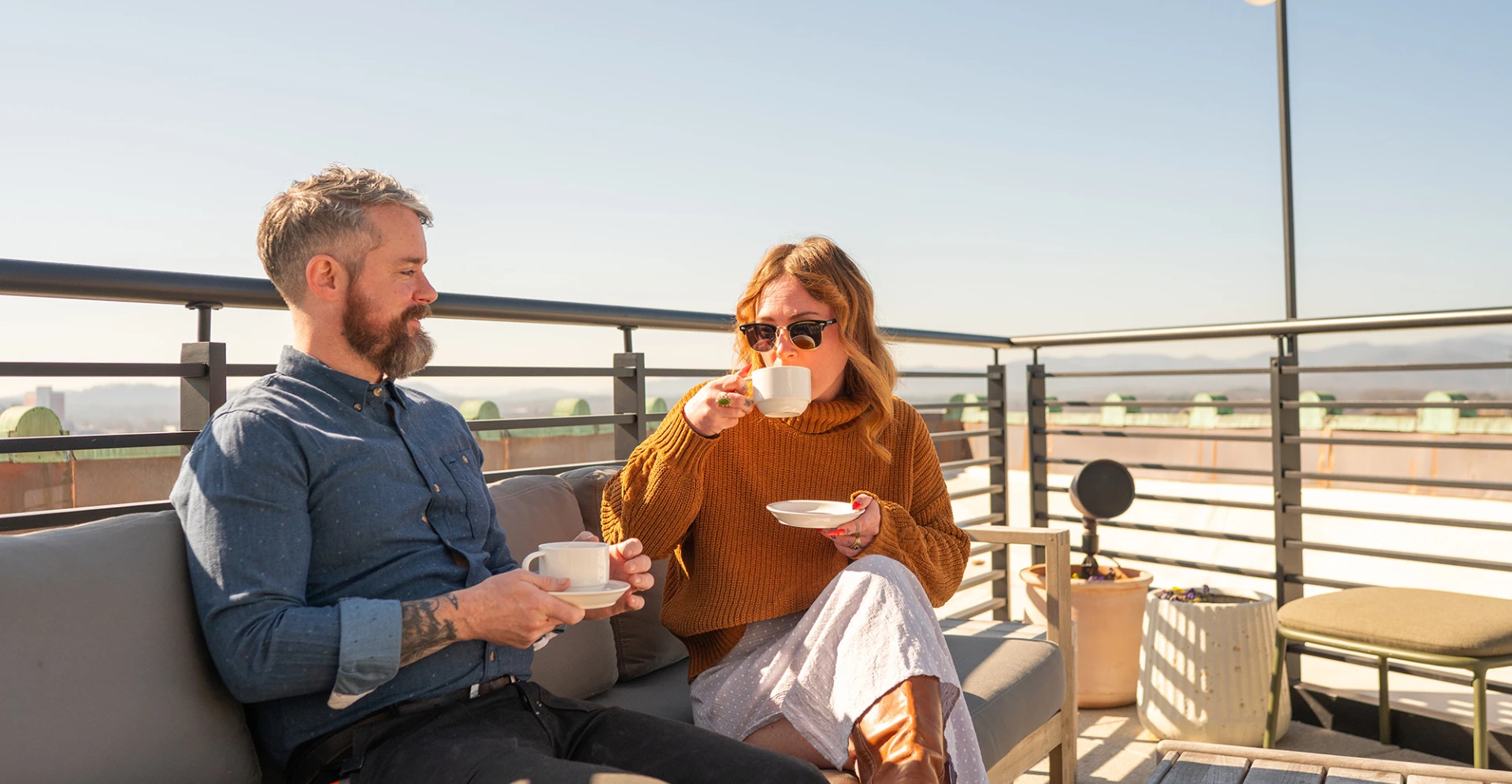 a man and woman sitting on a couch drinking coffee