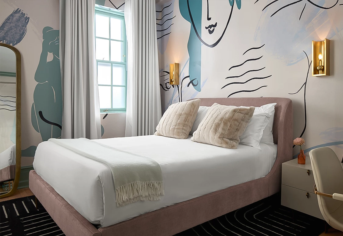 a bed with pillows and a wall with a painting on the wall