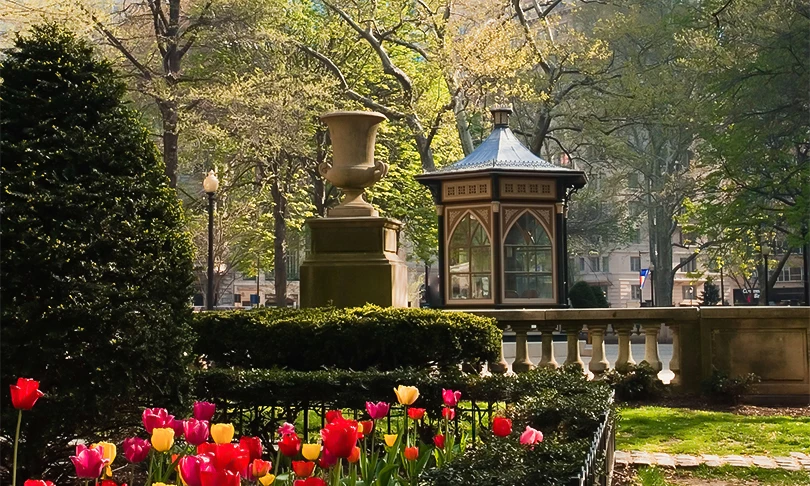 A park scene with a gazebo, statue, and colorful tulips.
