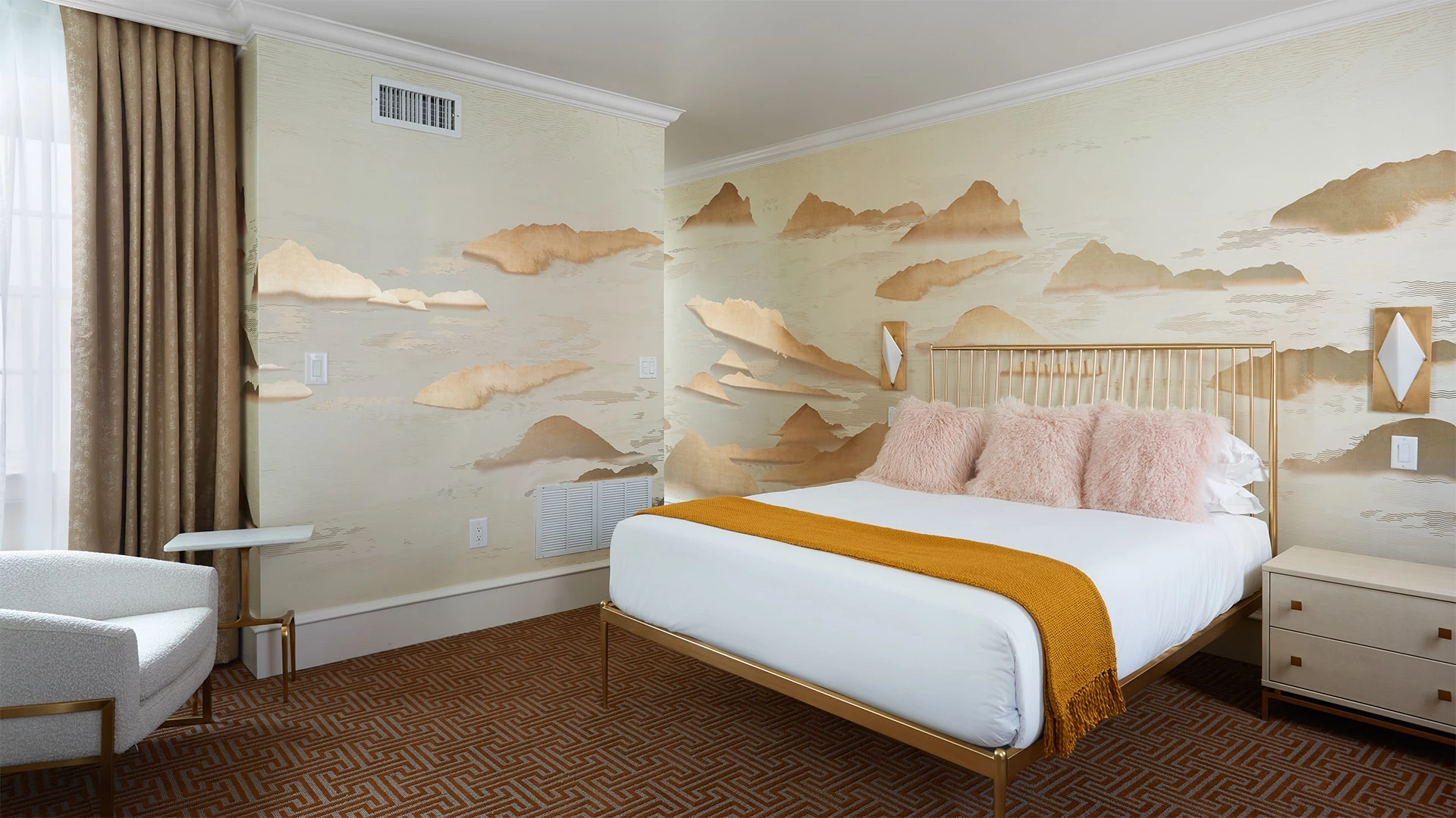 A hotel room with a bed, nightstand, chair, and wall mural