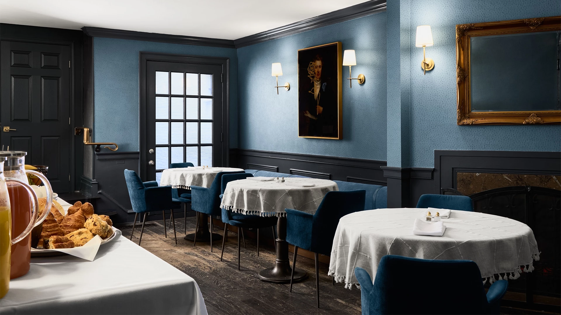 A dining room with blue walls, white tablecloths, and blue chairs.