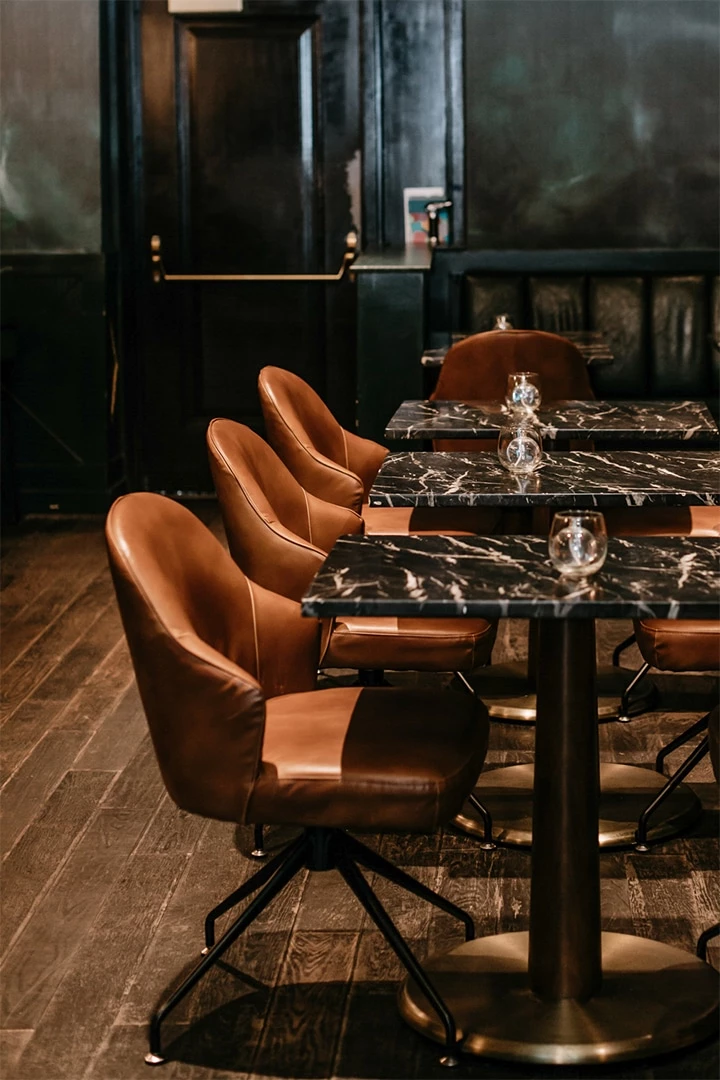 A dining area with a black marble table and brown leather chairs