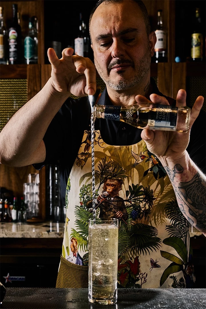 A bartender pouring a drink into a glass.