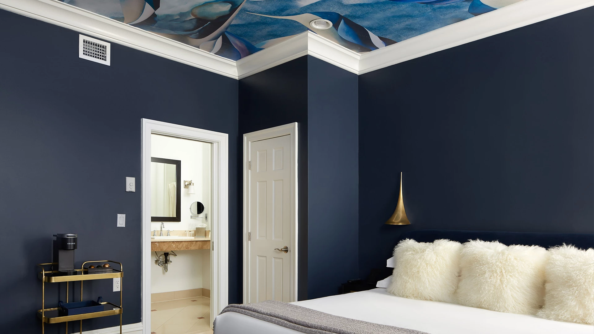 A luxurious bedroom with a large bed, nightstand, and coffee maker