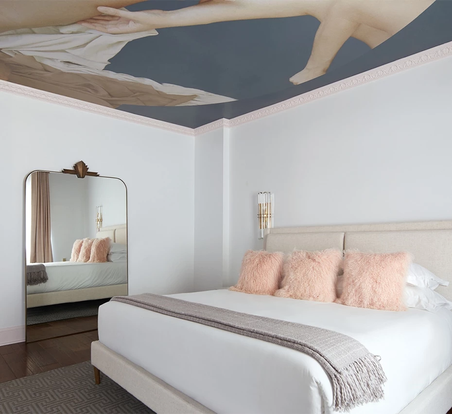 A luxurious hotel room with a large bed, white walls, and a ceiling mural.