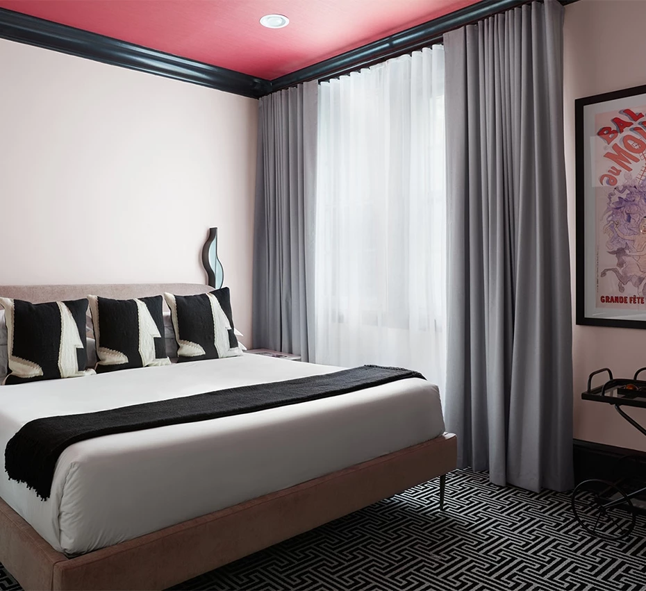 A wide view of a hotel room with a king-sized bed, window, and artwork.