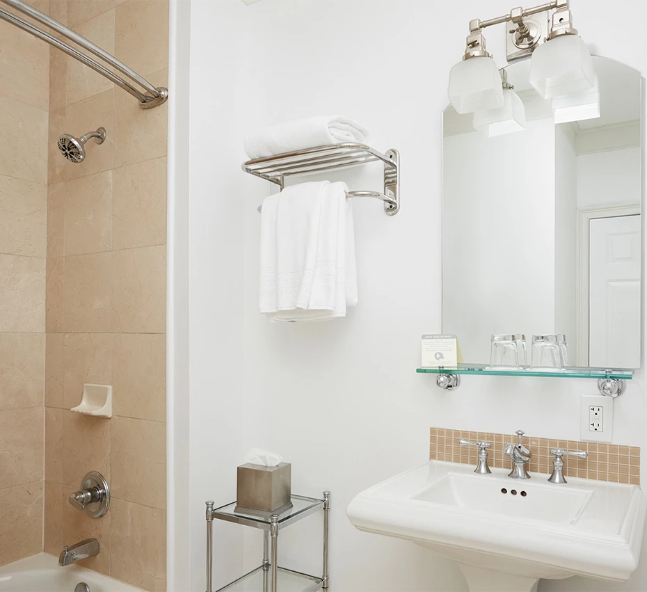 A clean bathroom with a tiled shower, double vanity, and mirror