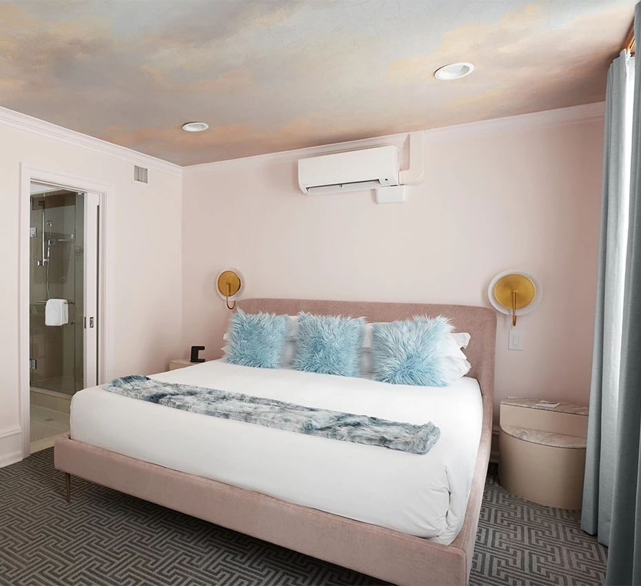 A hotel room with a large bed, nightstands, and a bathroom with a shower.
