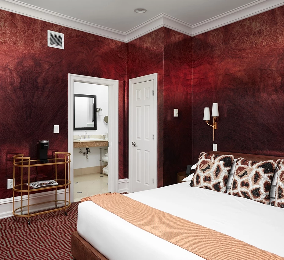 A luxurious hotel room with a king-sized bed, red walls, and a marble bathroom.