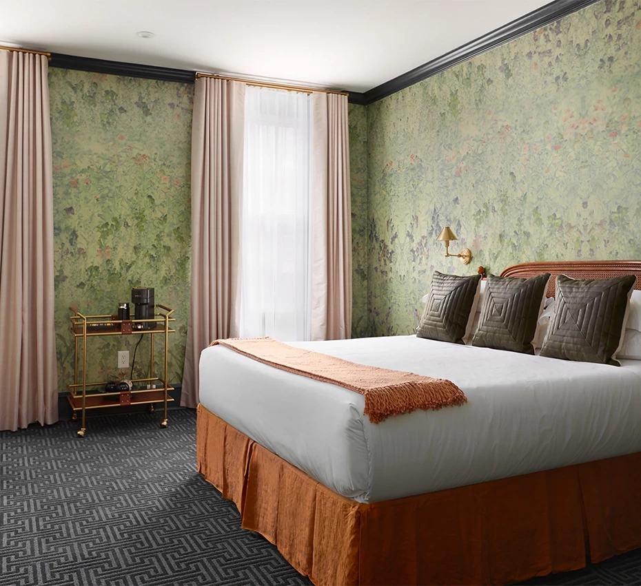 A hotel room with a large bed, dresser, and window